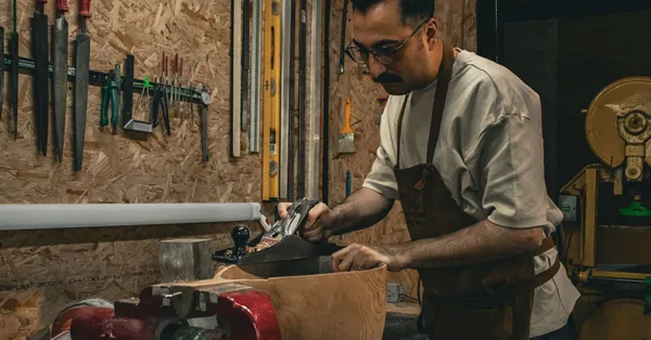 Carpenter using hand tools to shape wood in a workshop environment. craftsman working in a wood workshop