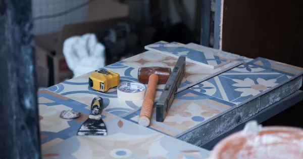 Tools and tiles on a construction site, ready for tiling work. Includes trowel, tape measure, and adhesive tape. tiling equipment laid out on a job