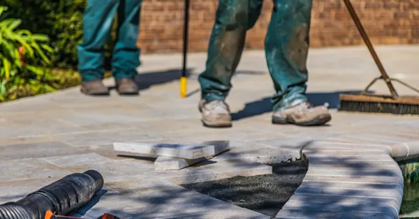 Workers laying tiles on an outdoor patio under sunlight. close up shot of tiled ground
