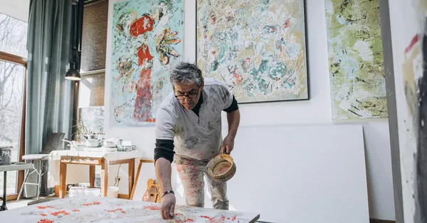 A skilled male painter working in his art studio, surrounded by abstract paintings. man painting a picture on a canvas in a studio