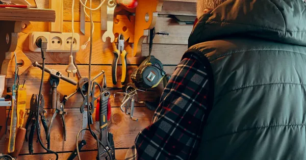 A person working in a wood-paneled workshop surrounded by tools. craftsperson in a cozy workshop setting