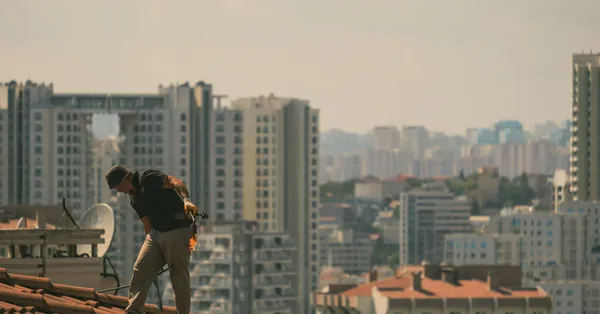 Construction worker on a rooftop in İstanbul with city skyline in the background. rooftop construction worker in istanbul skyline