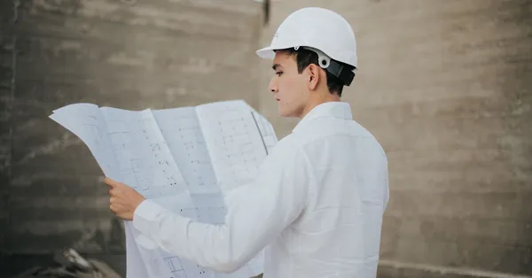 Architect examining blueprints at a construction site in Mexico. male architect looking at a plan layout