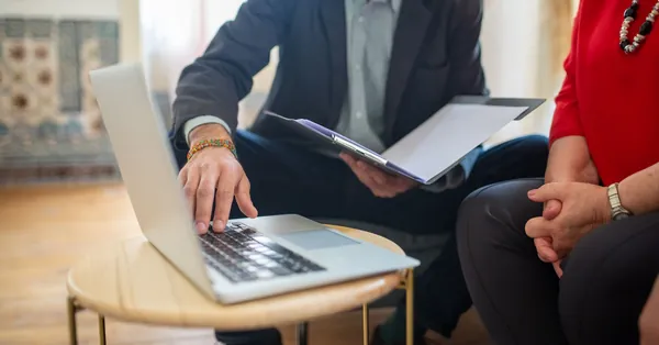 Professional meeting with a laptop and documents in an office setting. lawyer showing documents to a woman and using a laptop