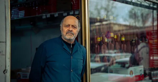 Senior man standing by his storefront in an urban area, showcasing a local business. portrait of a shop owner standing by his store