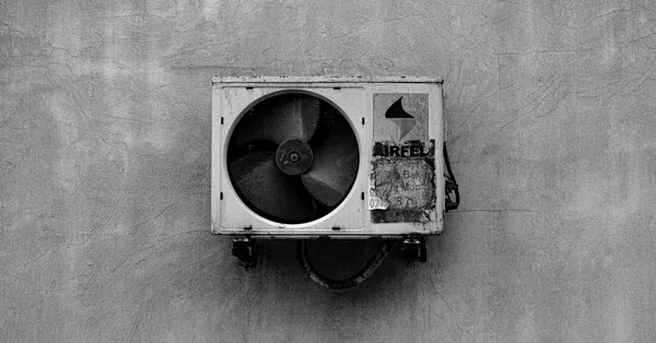 Monochrome image of a wall-mounted air conditioner on a concrete surface. black and white industrial air conditioner unit