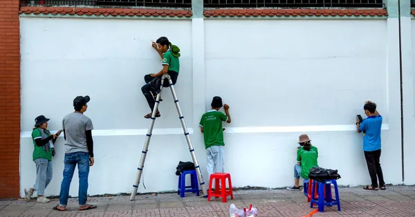 People collaboratively painting a mural outdoors, engaging in creative teamwork. people having conversation while working on the street