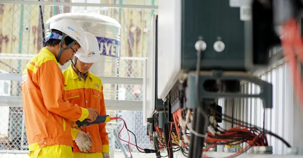 Two technicians with helmets working on electrical equipment outdoors, ensuring safety. men working with electrical wires