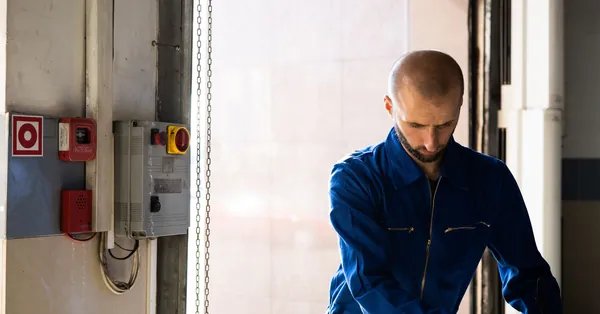 Caucasian male technician working indoors with PPE in industrial setting. operator wearing blue protective body suit