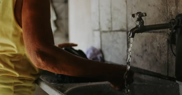 Close-up of a person washing hands under a tap in a rustic indoor setting. person washing hands in rustic indoor sink