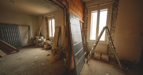 Interior view of a room under renovation with construction materials and a ladder. building during refurbishment