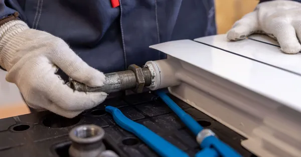 Close-up of a plumber installing a radiator pipe using specialized tools. professional plumber installing a radiator pipe